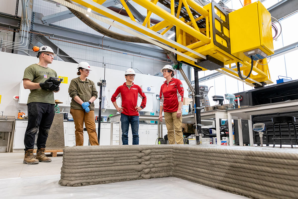 Downing consults with Zhou and Barry on their 3D printing test of a cement wall