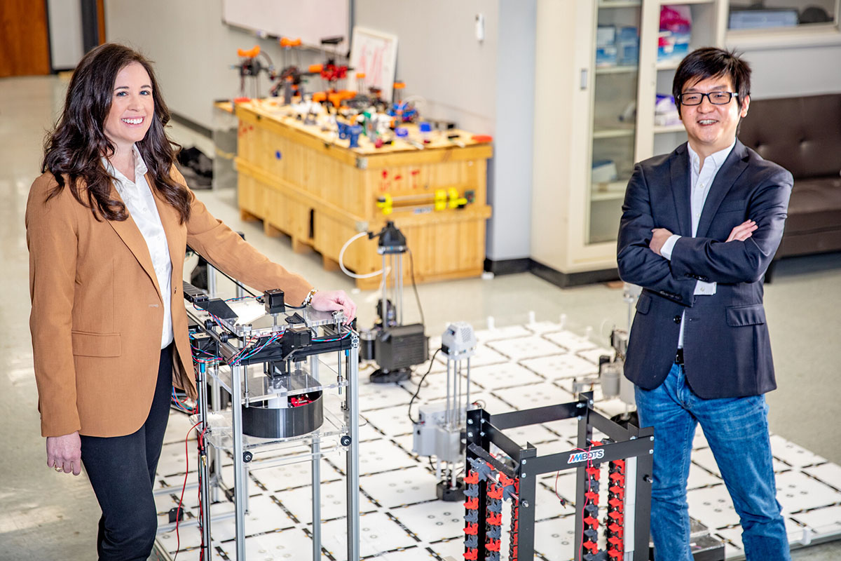 Michelle Barry and Wenchao Zhou stand next to 3d printers in a lab